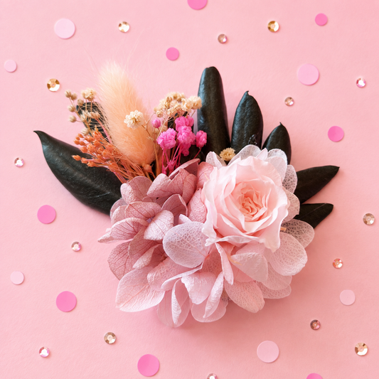 Boutonniere badge broche fleurs stabilisees rose poudre peche fuchsia et feuillage vert sombre pour mariage